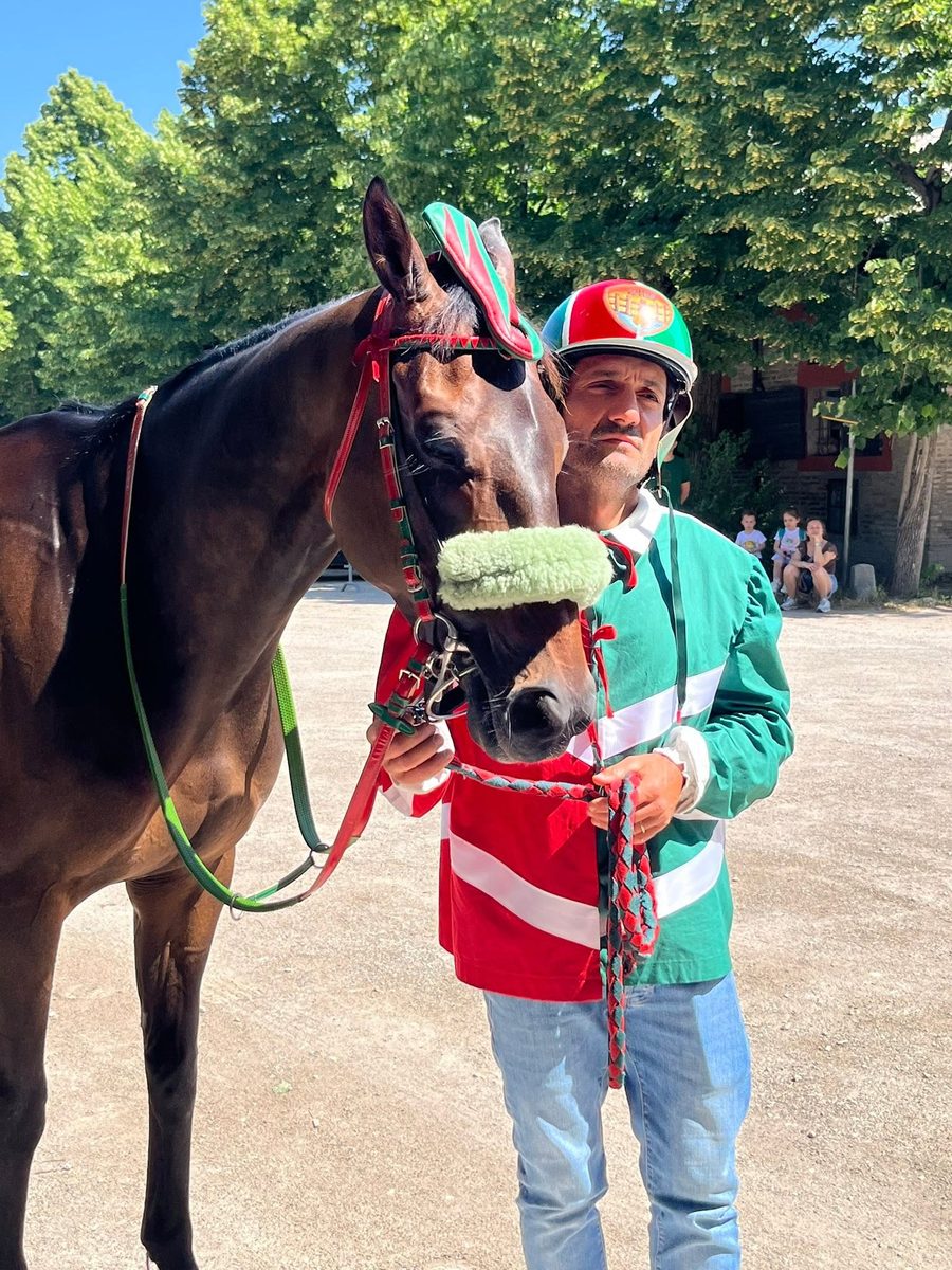 Giosuè Carboni in casacca rosso e verde accanto al cavallo bardato con i colori del Borgo San Luca
