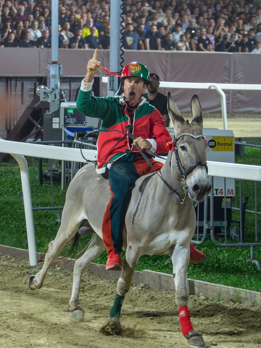 Denis Del Duca in casacca rosso e verde corre sull'asina in pista, col dito alzato
